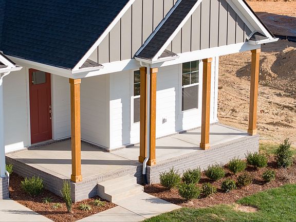 Exterior of home with white and gray siding and wood accent columns around covered front porch