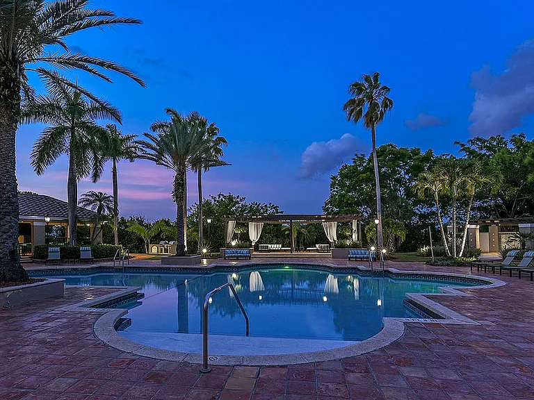Pool at dusk with palm trees and cabana views.