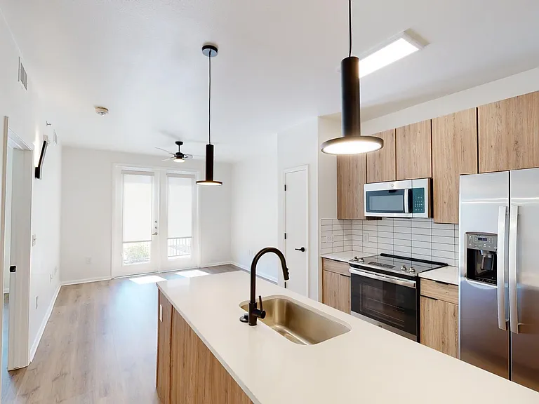 Apartment Kitchen with Stainless Steel Appliances, Dining and Living Room with Wood Style Flooring and Patio/Balcony.