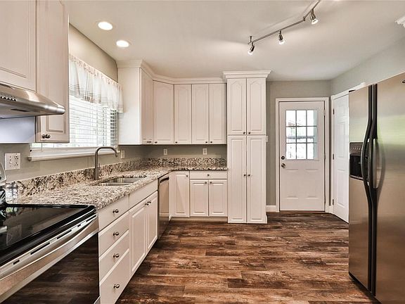 Updated white kitchen offers 42" cabinets with crown molding, granite counters, exterior door to carport and heated floor