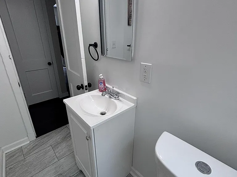 Well-kept bathroom with a single-sink vanity, wall mirror, and tile flooring for easy cleanup and daily convenience.