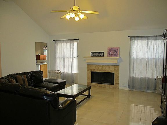 The spacious den has high ceilings, sleek tile flooring and a beautiful fireplace with gas connectio