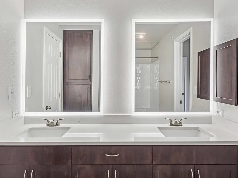 Upgraded bathrooms feature quartz countertops and backlit mirrors.