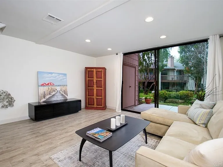 This spacious living room, part of a 1000sqft condominium, offers a welcoming and airy atmosphere. The large sliding glass doors lead to a private patio, allowing for ample natural light and easy access to outdoor living.
