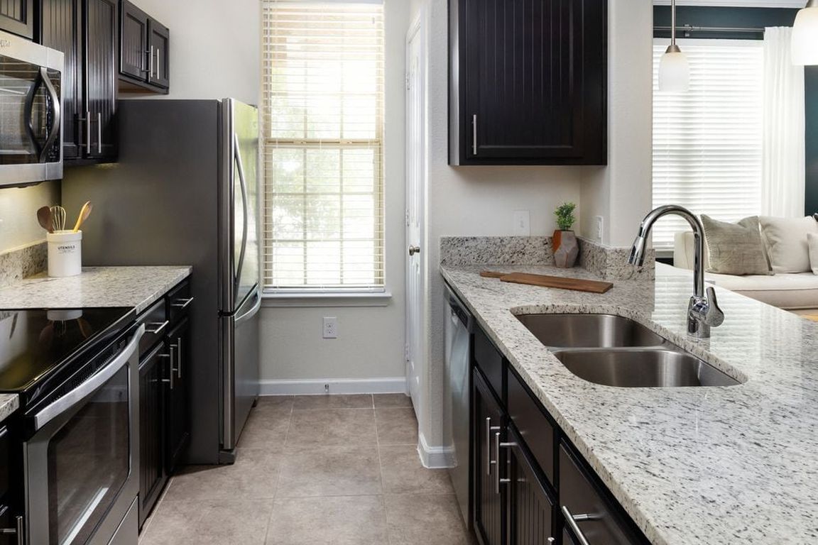 Kitchen with espresso cabinetry, granite countertops, and stainless steel appliances