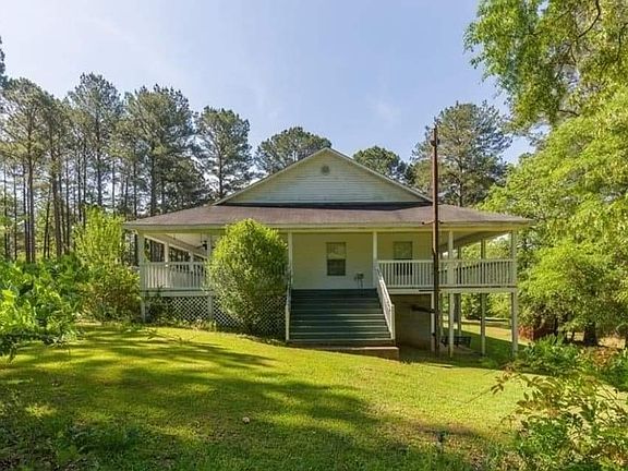 Another exterior view that shows the side of the home with a staircase that leads to wrap around porch.