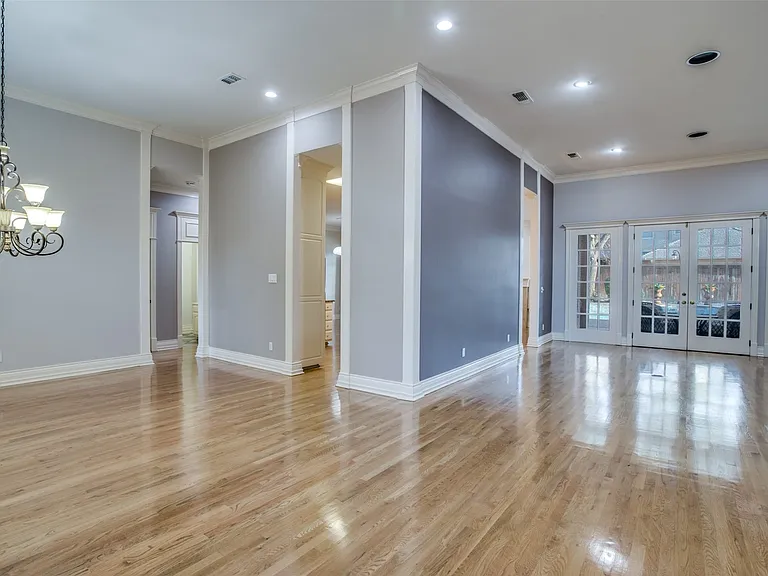 View as you enter the home. Wood style floors throughout the main living areas. Straight ahead is the spacious living area. To the left is the formal dining space. The doorways lead to the kitchen, 2nd dining-breakfast space, den, bedroom with bookshelves