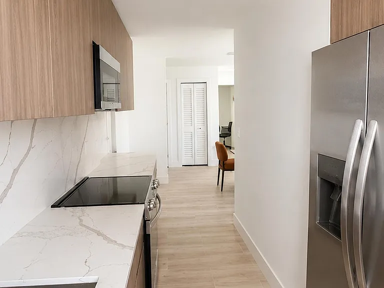 Streamlined galley kitchen with stainless-steel refrigerator, built-in microwave, and generous counter space for meal prep.