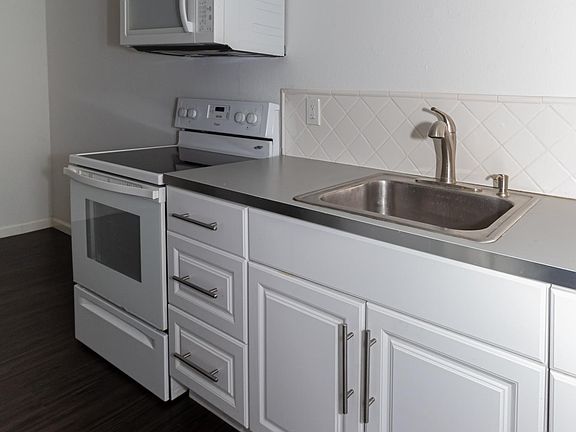 Kitchen with lower cabinet space, grey countertops, and stove/oven