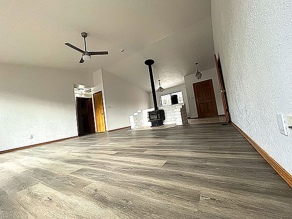 This grand living room boasts vaulted ceilings, new ceiling fan, floors, and paint.