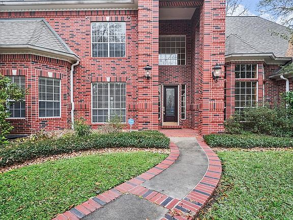 A brick lined walkway leads the way to the covered front door.