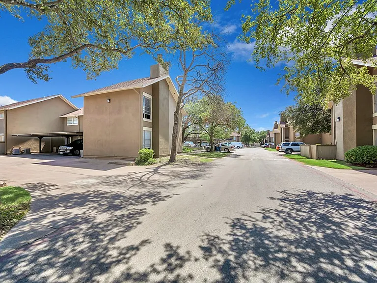 Tree-lined residential street with shaded parking and peaceful community setting at Watersong Villas Apartments in North Dallas.