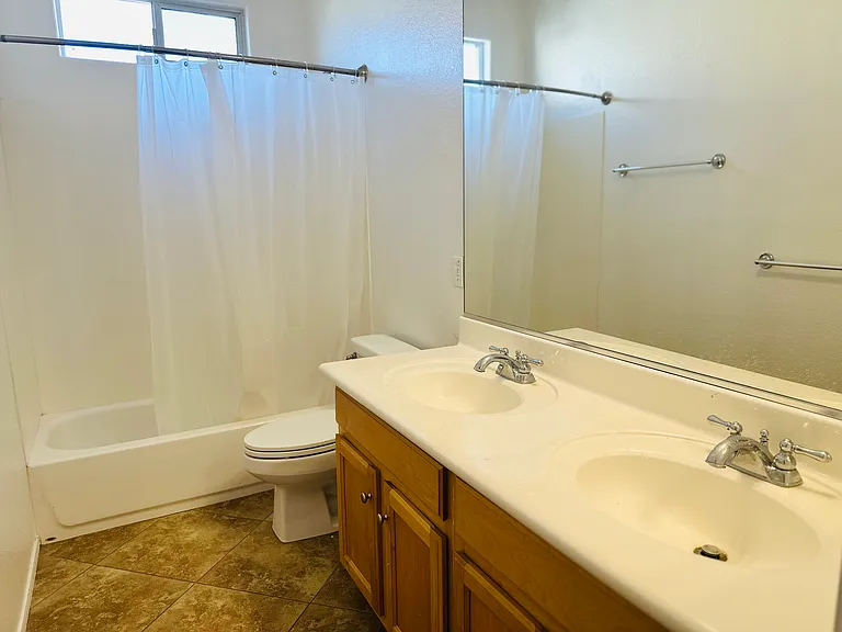 Full bathroom with a dual-sink vanity, generous counter space, and a tub-and-shower combination.