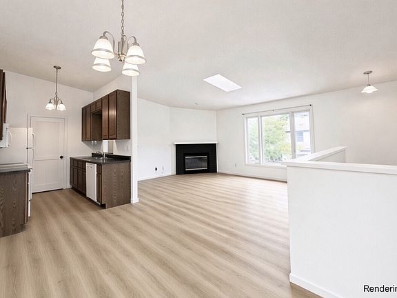 Open layout living area with abundant natural lighting, adjacent to galley style kitchen and dining area.