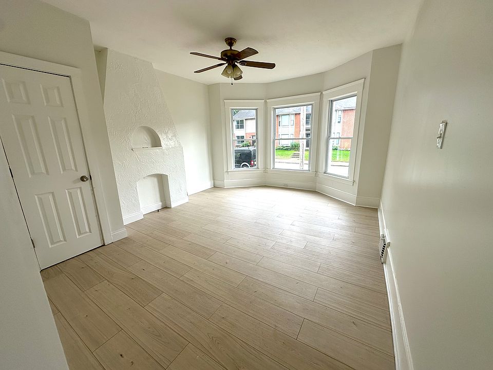 Spacious living room with sunny bay windows, coat closet, and chimney detail