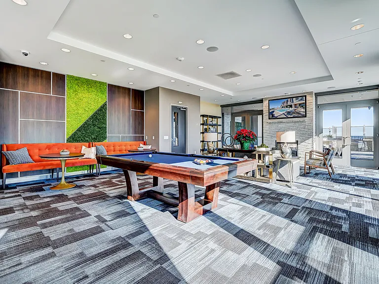 Resident lounge area with bar top seating, catering kitchen, lounge seating, entertainment area, and rooftop pool access