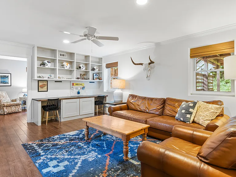 Second living room with two desk spaces, comfortable leather couch and lounge chair, Smart TV, and a ceiling fan.