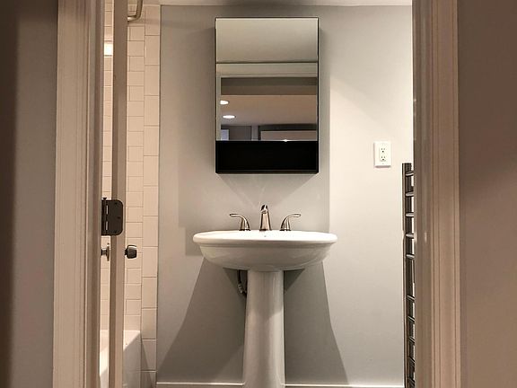 Bathroom with full tub, heated basalt mosaic floor, and heated towel rack