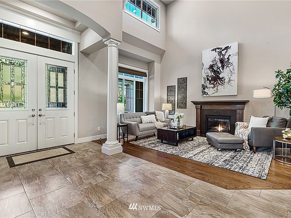 Soaring 20+ ft ceilings open to the formal living area with hardwood floors, window covering on a remote control and granite surround gas fireplace with a mahogany mantle.
