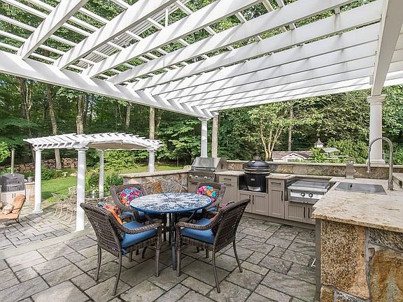 The stunning two-tier stone patio features granite counters and Walpole Woodworker pergolas with retractable awnings.