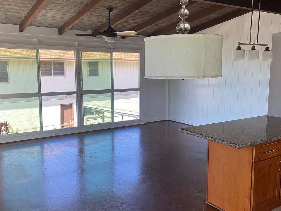 Living room:
Bright open living area with vaulted exposed-beam ceiling and hardwood floors.