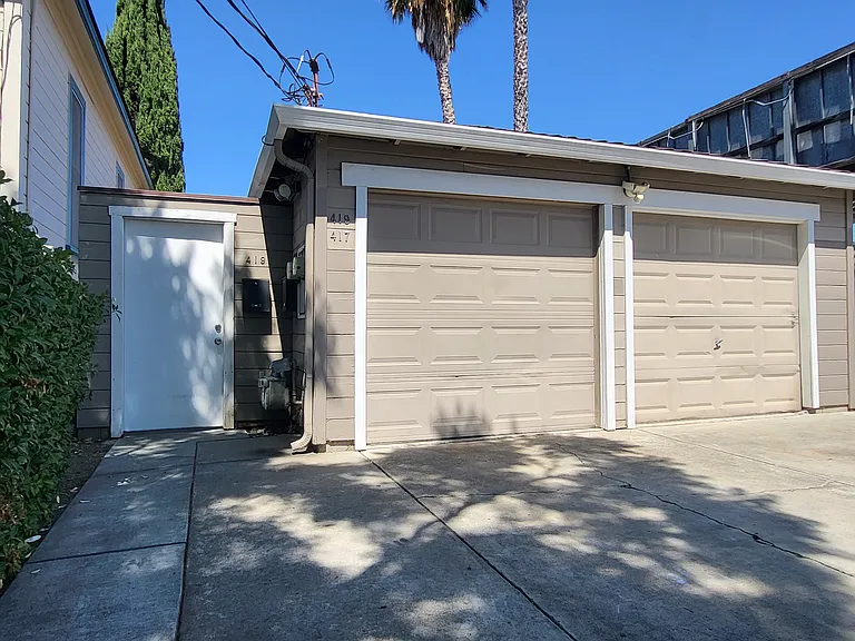 Front of building showing off-street parking, garage, and side gate entrance.