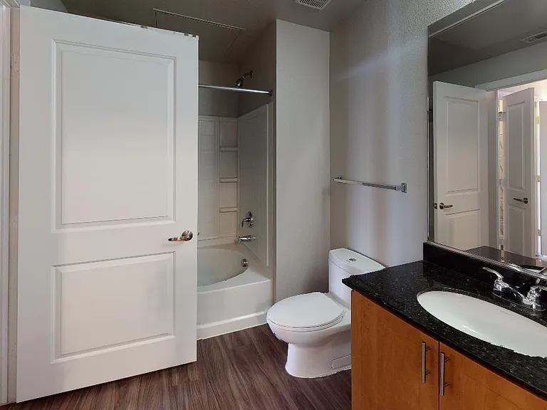 Apartment bathroom with large soaking tub and wood-style flooring.