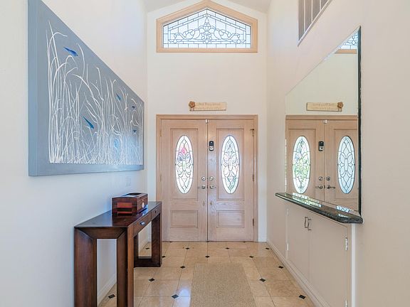 Entryway through double door, chandelier, vaulted ceiling and marble floor