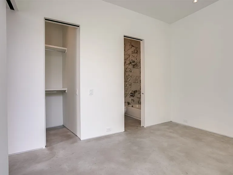 Spacious room with concrete flooring, recessed lighting, and a built-in closet featuring shelving and a hanging rod