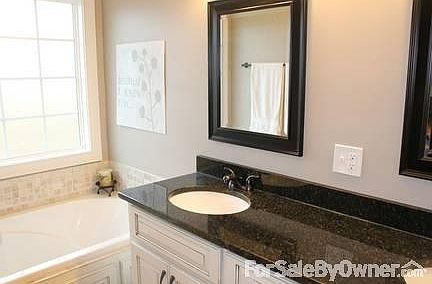 Modern bath with custom cabinetry, granite, and beautiful tile floors.