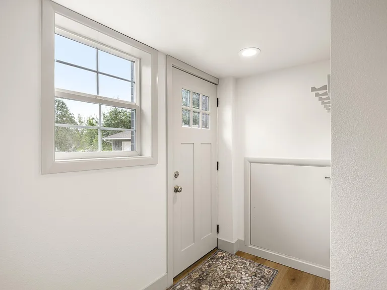 Entry foyer with a large window, paneled front door, and a convenient under-stair storage closet for everyday gear.