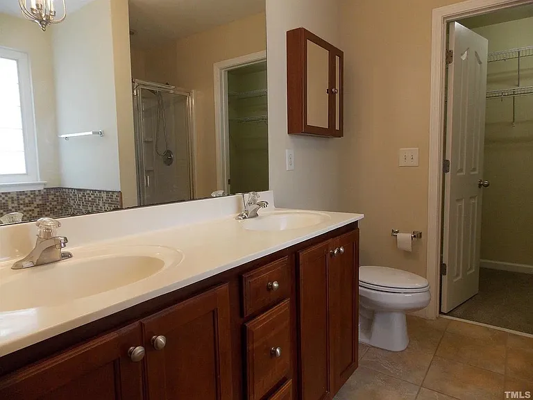 Primary bathroom with dual vanities, bathtub, shower and walk in closet