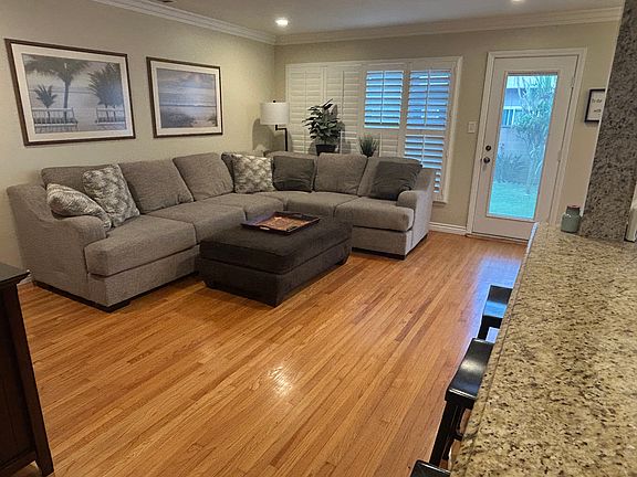 Open Living room with wood floors, shutters, and door to back yard.