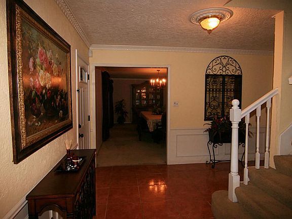  Beautiful foyer with tile flooring, custom crown molding, chair railing and lovely upgraded light fixture