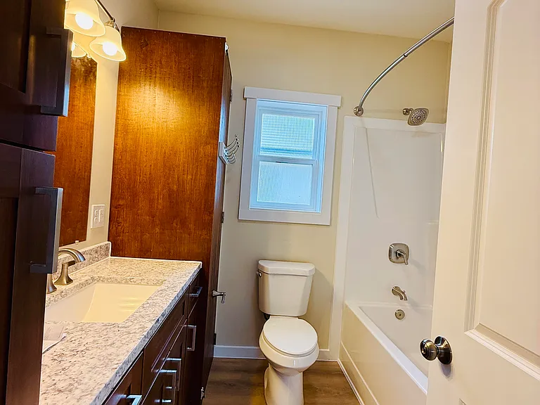Large full-size bathroom with full size tub and shower, hot water heater, toilet, linen closet and clothes washing station