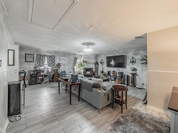 Spacious living area with attic access, a wood fireplace, and tiled flooring, with amazing lighting.