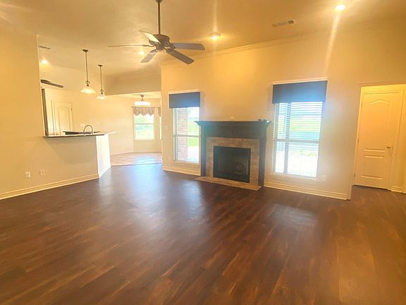 Spacious living room with view of back patio & pool, ceiling fan, recessed lighting, LVP flooring, propane gas fireplace with decorative mantle