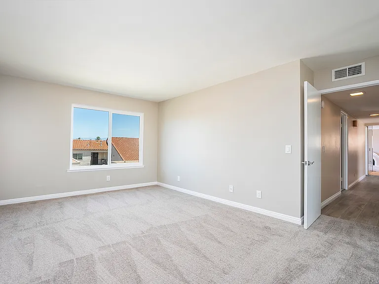 Spacious primary bedroom, with new windows, carpet, paint, and elegant baseboards.