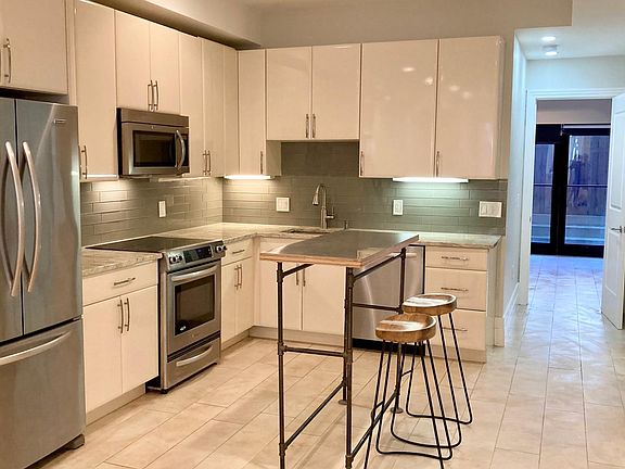Kitchen Aid stainless steel appliances, glass tile backsplash, stone counters, plenty of cabinet space, and an island with stools