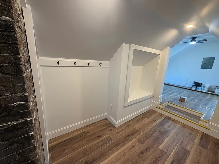 Immediately behind the chimney to the left is shelving. Then there are hooks to hang jackts. Further back is the bench to sit to take off boots and shoes. Then there is the grand entrance way to the main room.