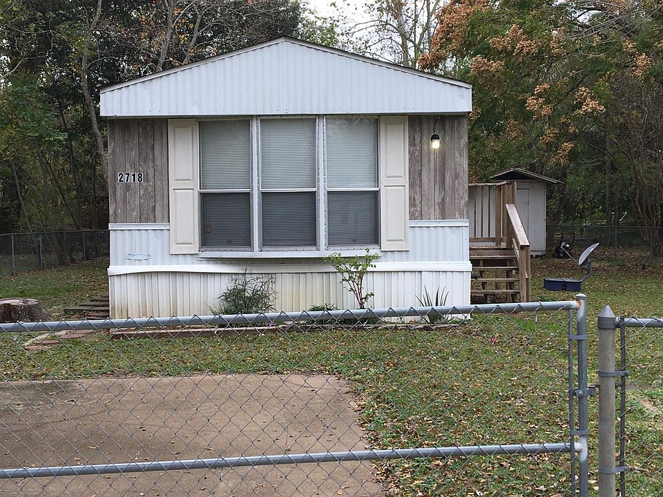3-2 mobile home with 2 porches and storage building on fenced lot.