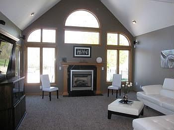 The living room has vaulted ceilings and natural light with an entire wall of windows.