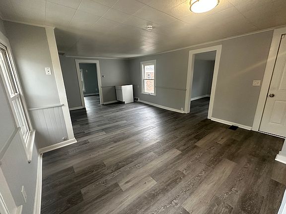 Spacious, sun-filled living room with brand new flooring, modern lighting, and fresh paint throughout.