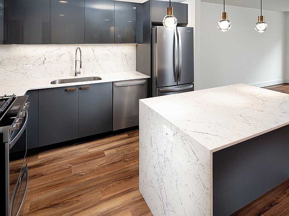 Signature Collection kitchen with pendant lighting, quartz stone countertop with waterfall edge, cabinetry with matte and high gloss finish, and SMART stainless steel appliances