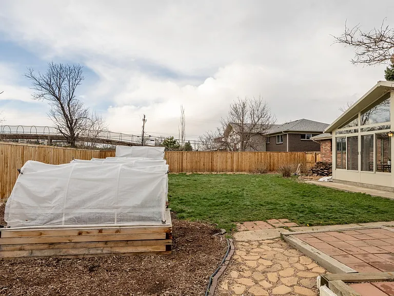 View north from in the garden, showing raised garden beds, privacy fence, lawn, and the sun room.
