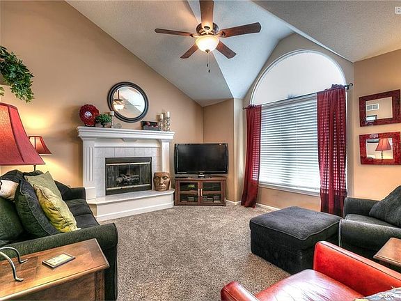 The living room features a beautiful vaulted ceiling, a new ceiling fan, fireplace and new carpet.