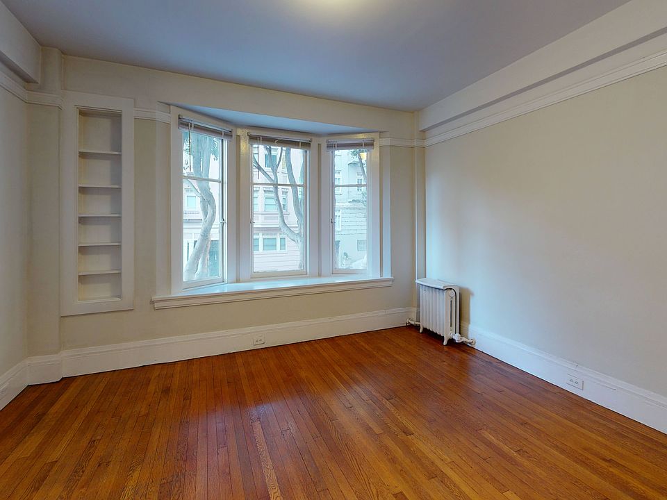Bright room with hardwood floors, bay window, and radiator