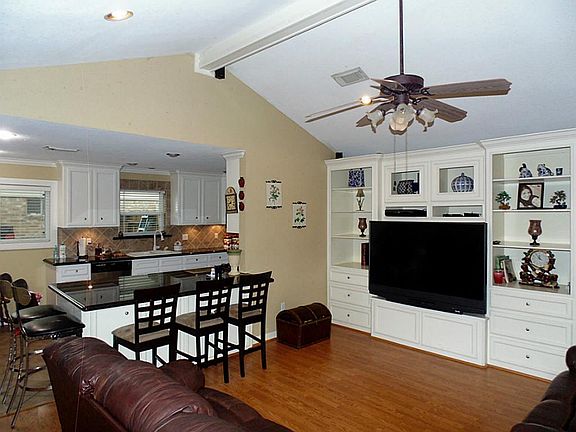 This living room boosts custom built shelving, the kitchen is open to the living room.