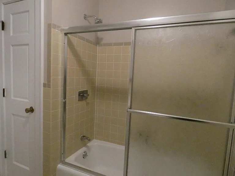 Tiled shower, with large linen closets.