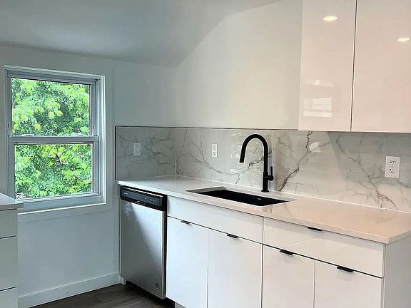 Sleek white cabinetry with soft-close doors, matte black fixtures, and under-cabinet lighting.